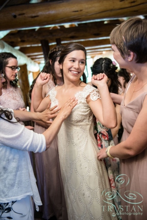 Bridesmaids helping a bride into her wedding dress at The Breckenridge Nordic Center.
