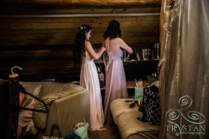 A bridesmaid helping another bridesmaid into her dress.