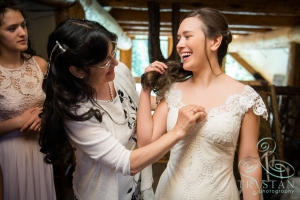 A bride laughing as her mom straightens her necklace.