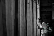 A bride looks out the curtains of a dark room as she waits nervously before the ceremony.