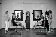 A bride and her bridesmaid sitting in makeup chairs as they get their hair done before a wedding.