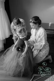 A bride helping a flower girl get ready before she gets ready for the wedding.