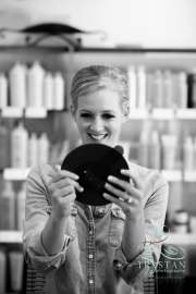 A bride with a smile of approval as she looks in a hand mirror at the finished hair and makeup product before the wedding.