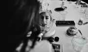 A bride looking into a small makeup mirror before the wedding.