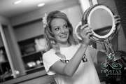 A bride nervously beaming as she sees herself for the first time in a mirror before the wedding.
