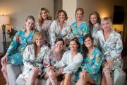 A bride and her bridesmaids posing for a photo in their floral bridal robes before the wedding.