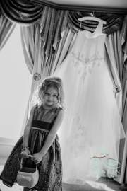 A flower girl standing near the wedding dress before the wedding.