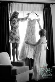 A bride and her mother carefully getting the wedding dress down from the window before the wedding.