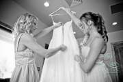 Two bridesmaids preparing the dress to be put on the bride before the wedding.