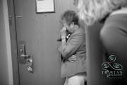 A bride's grandmother stands crying softly in the corner of the room because her granddaughter is so beautiful before the wedding.