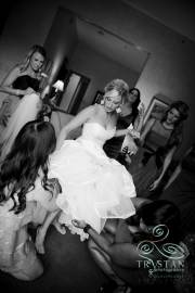A photograph of a bride getting her garter put on her leg before the wedding.