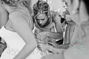 A photo of a bridesmaid's look of concentration as she ties the back of the bride's dress before the wedding.