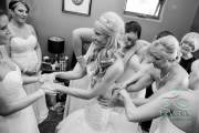 A bride squeezes her friend's hands and tries to smile as the dress is cinched more and more tightly before the wedding.