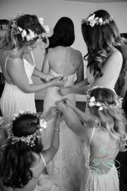A photograph of a circle of hands working on the back of a bride's dress before the wedding.