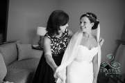 A bride smiles at her mother as her mother puts the final touches on the veil.