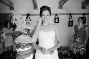 A bride nervously smiles as her mother helps put in her earrings.