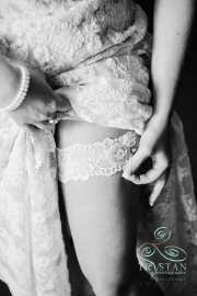 A bride carefully adjusting a delicate lace garter.