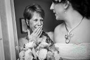 A mother crying with stunned joy as she looks upon her daughter for the first time on the wedding day.