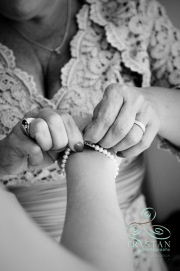 A mother's hands as she carefully fastens her daughter's delicate pearl bridal bracelet before the wedding.