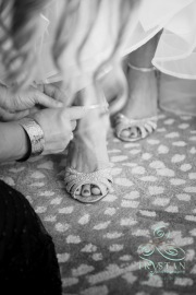 A close-up photograph of a brides feet as they put on her shoes.
