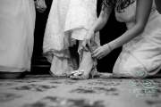 A bridesmaid fastens the strap on a bride's heels.