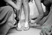 A cute shot of a bride's legs and shoes with the bridesmaids hands around them.