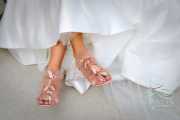 A color photograph of a bride playfully crossing her feet for a shot of her pink heels.