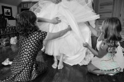 A mother and the bridesmaids digging around in the layers underneath the dress to make sure everything is fastened.