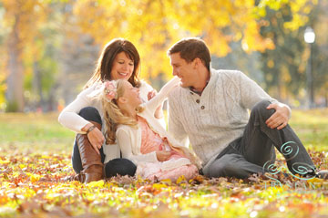 A portrait of a family laughing together while sitting in fallen leaves in Autumn in Colorado Springs.