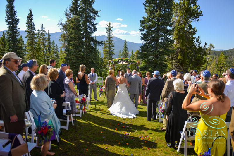 A photography of a bride being walked down the aisle by her mother and father at a wedding ceremony at V3 Ranch in Breckenridge, Colorado.