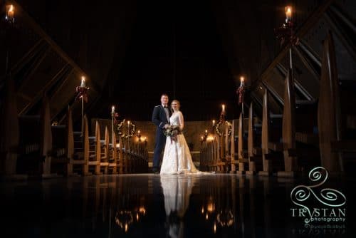 A Major and his bride stand in the darkened aisle of the Air Force Academy Chapel in the light of candles.