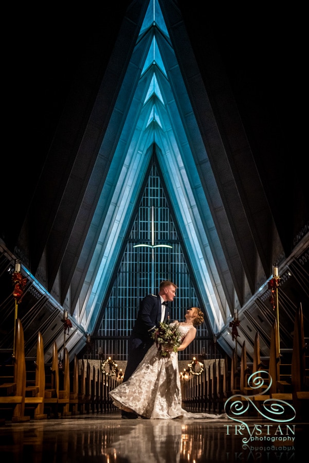 A bride and groom dipping in the aisle at The Air Force Academy Chapel at night.
