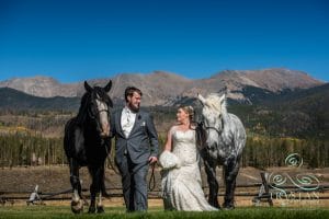 A bride and groom walking with horses at Devil's Thumb Ranch