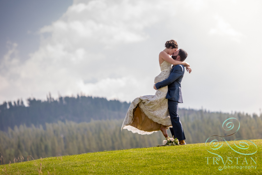 A photograph of a bride and groom passionately embracing with the mountains behind them at their wedding ceremony at Tiger Run in Breckenridge, Colorado.